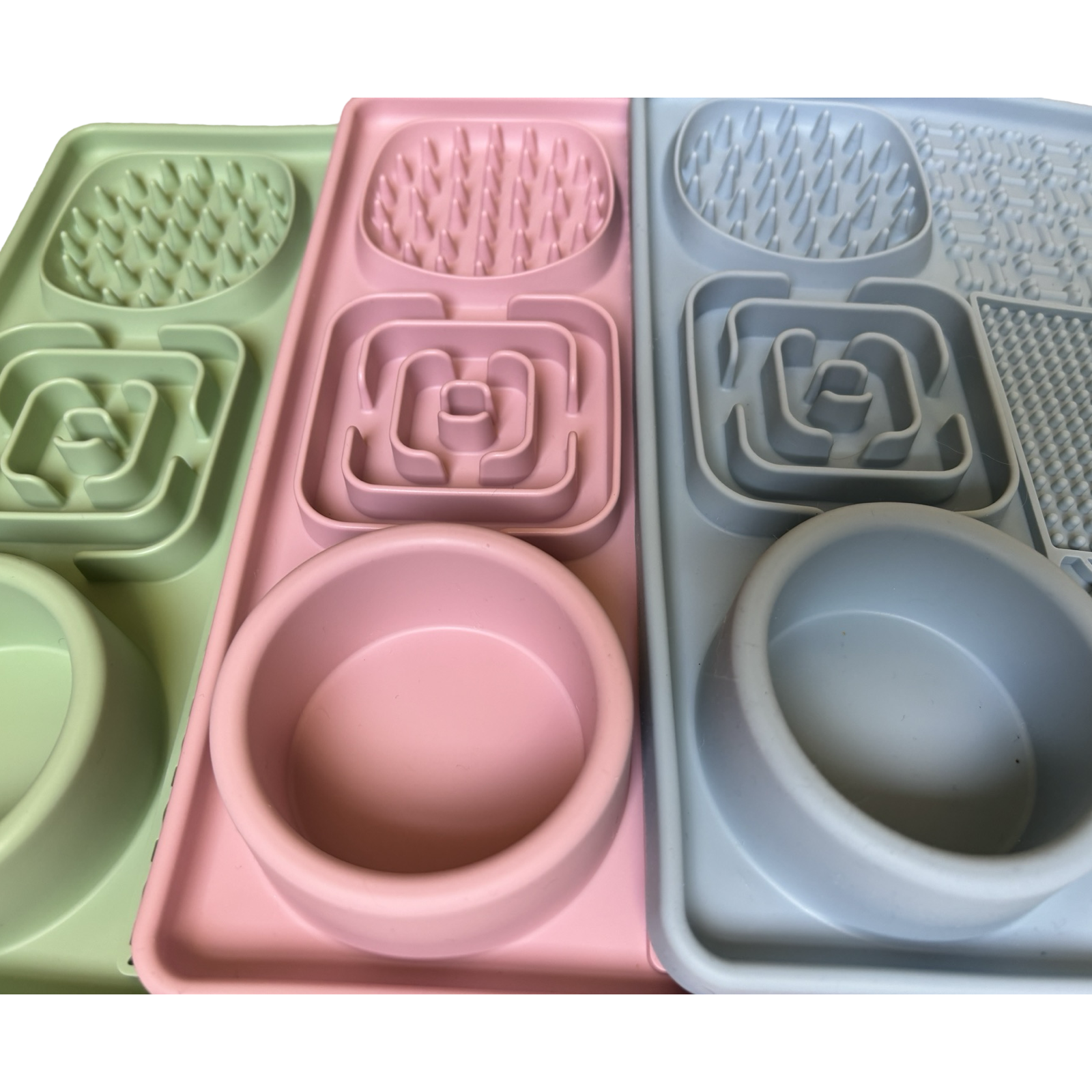 Three colourful dog lick mats in pink, green, and blue.